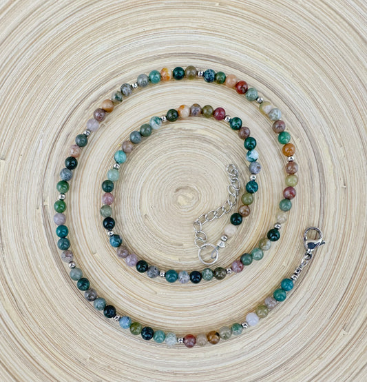Multicolored beaded necklace on a textured beige surface