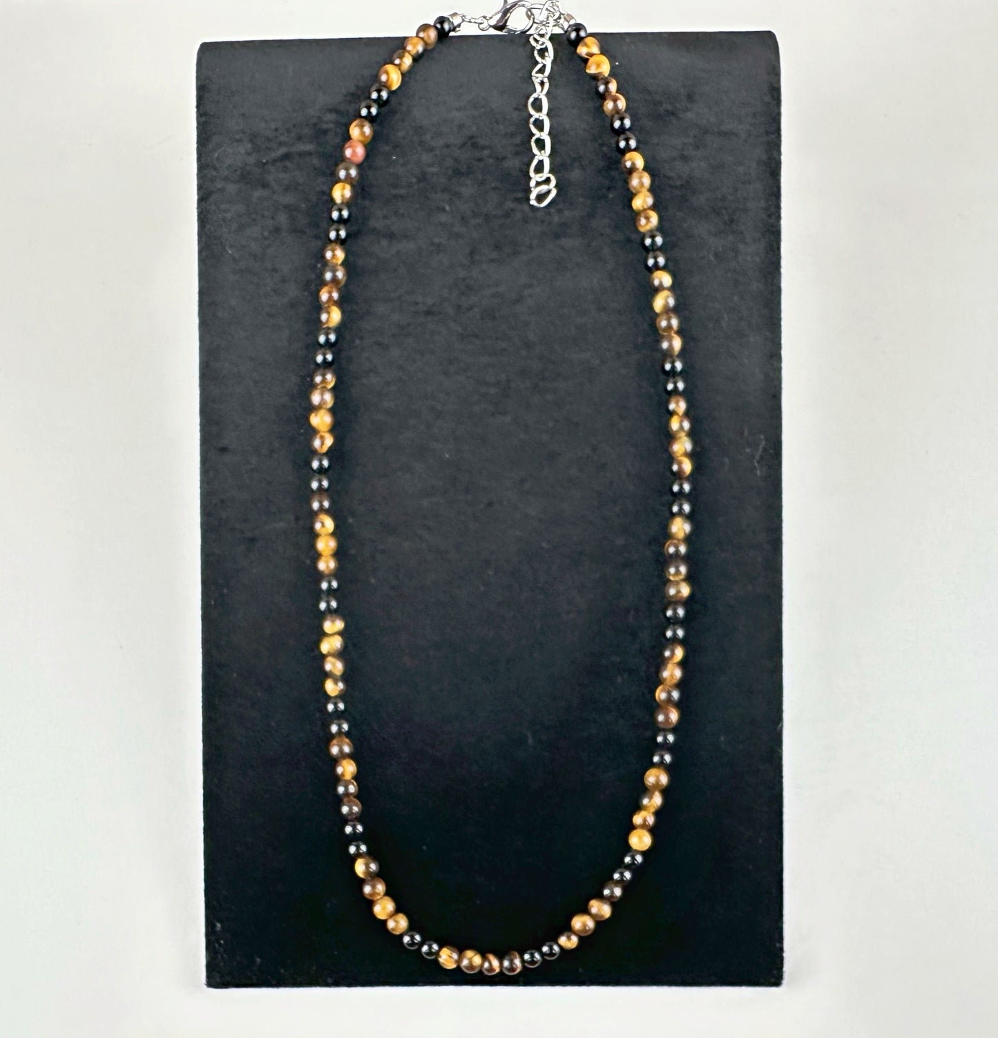 Beaded necklace on a black stand with a white background
