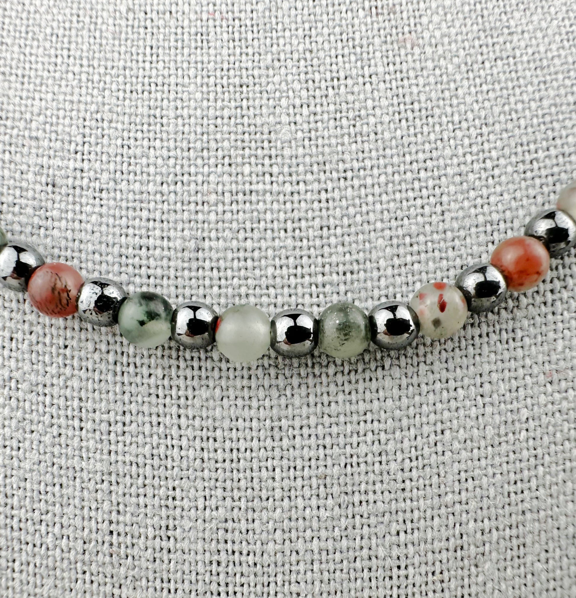 Beaded bracelet with silver and multicolored beads on a textured fabric background