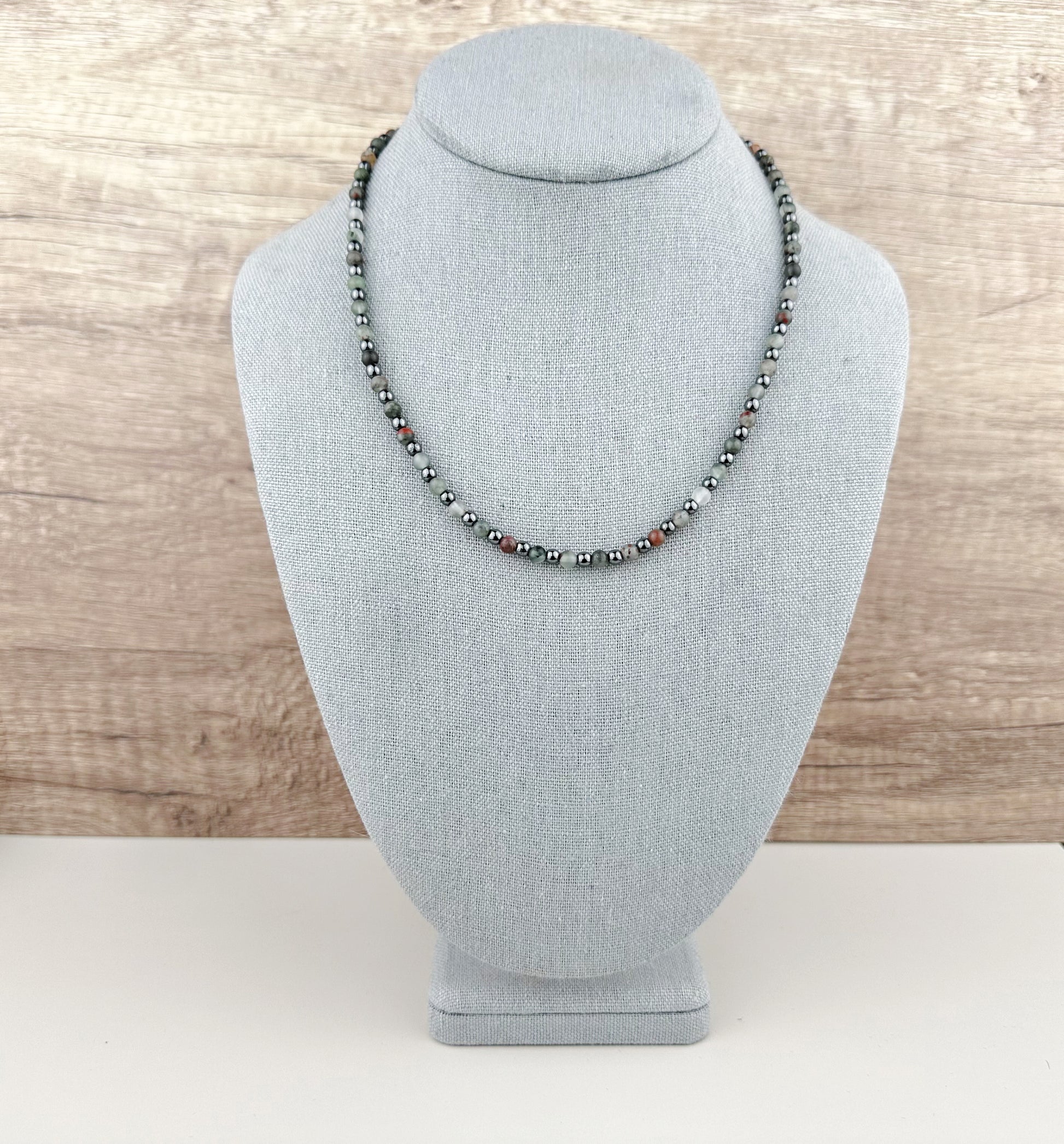 Necklace on a gray mannequin bust with a wooden background