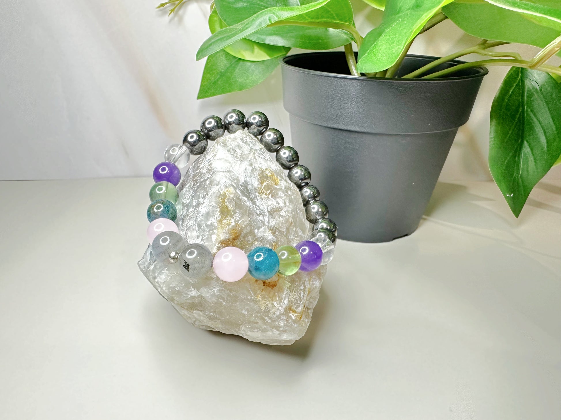 Beaded bracelet on a crystal with a potted plant in the background
