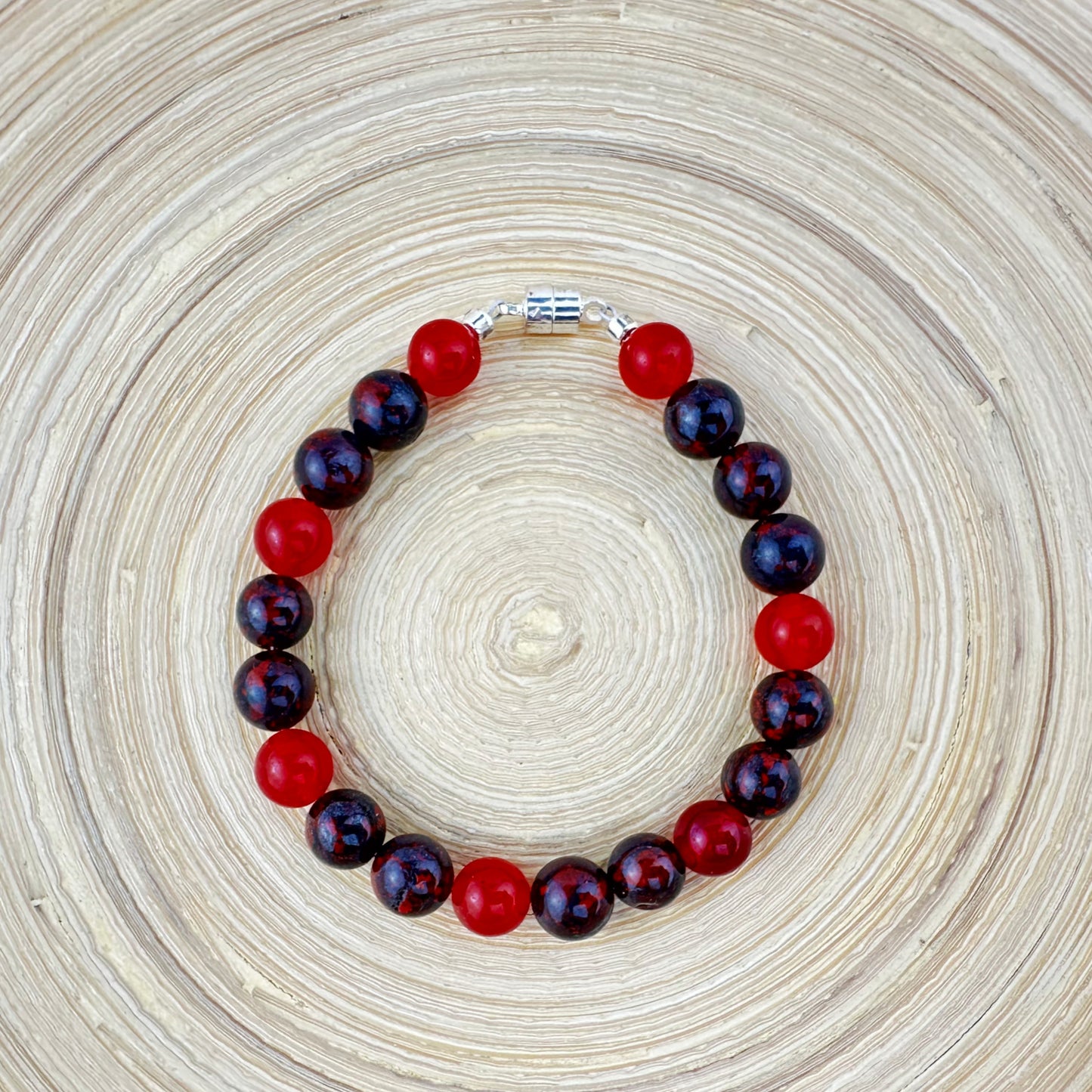 Bracelet with red and dark purple beads on a woven surface