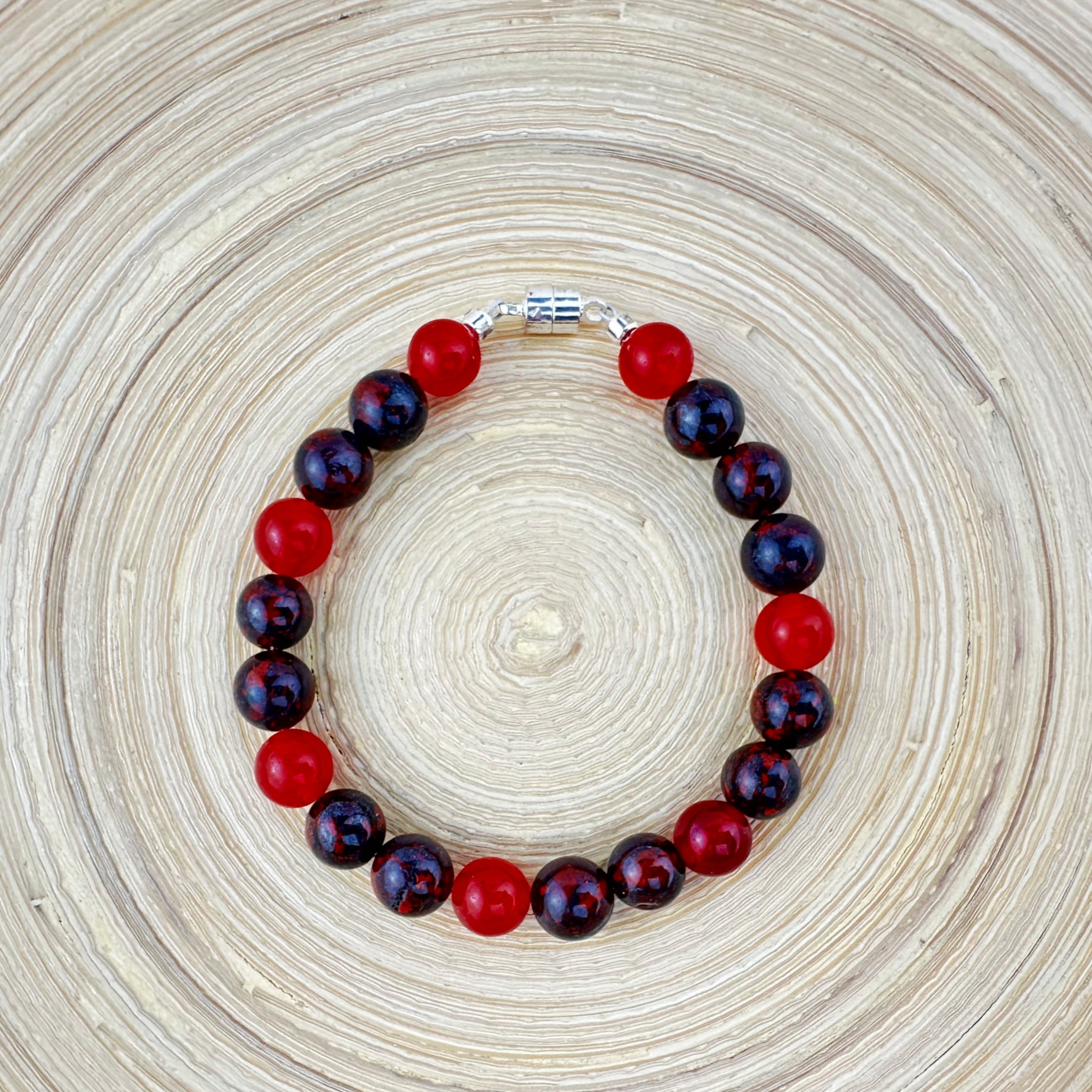 Bracelet with red and dark purple beads on a woven surface