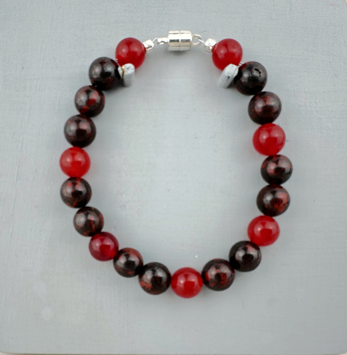 Beaded bracelet with red and brown beads on a light gray background