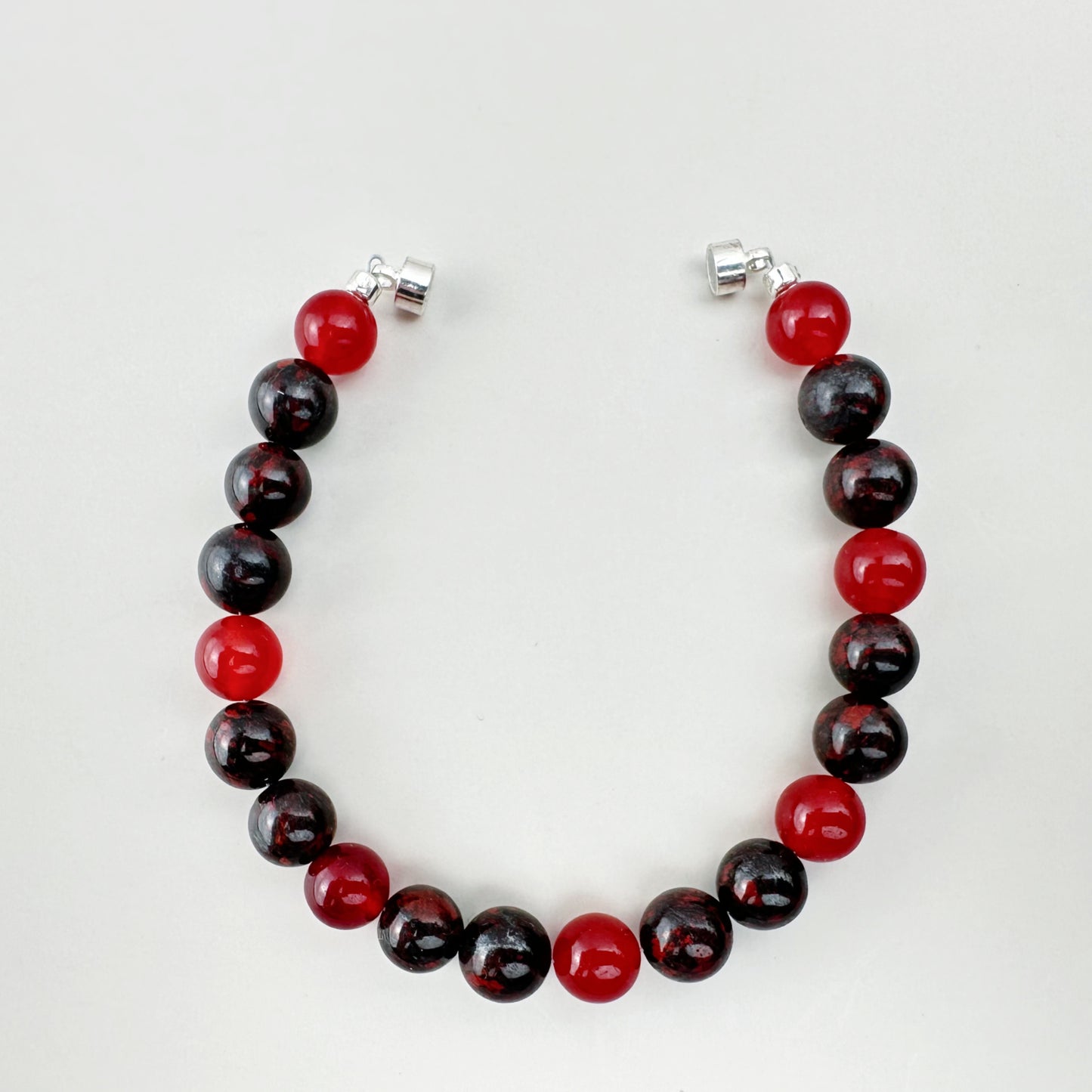 Beaded bracelet with red and black beads on a white background