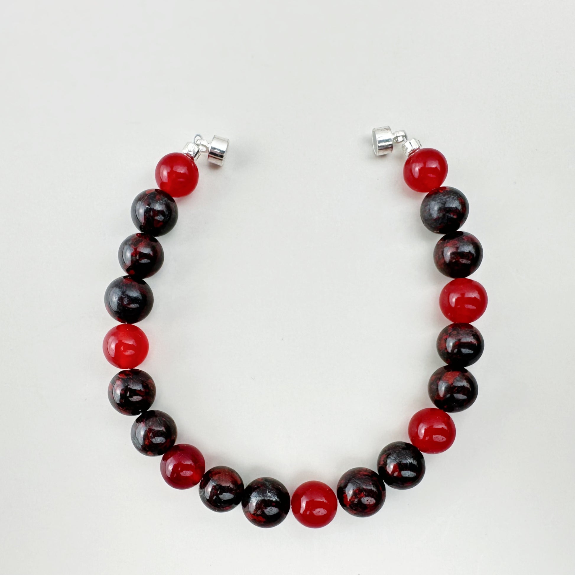 Beaded bracelet with red and black beads on a white background