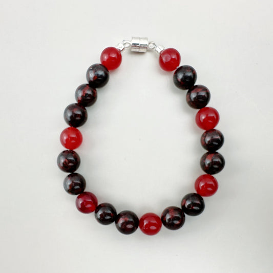 Beaded bracelet with red and black beads on a white background