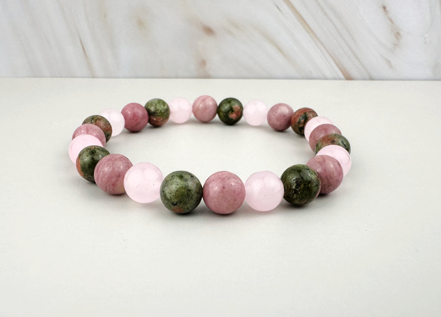 Bracelet with pink and green beads on a white surface