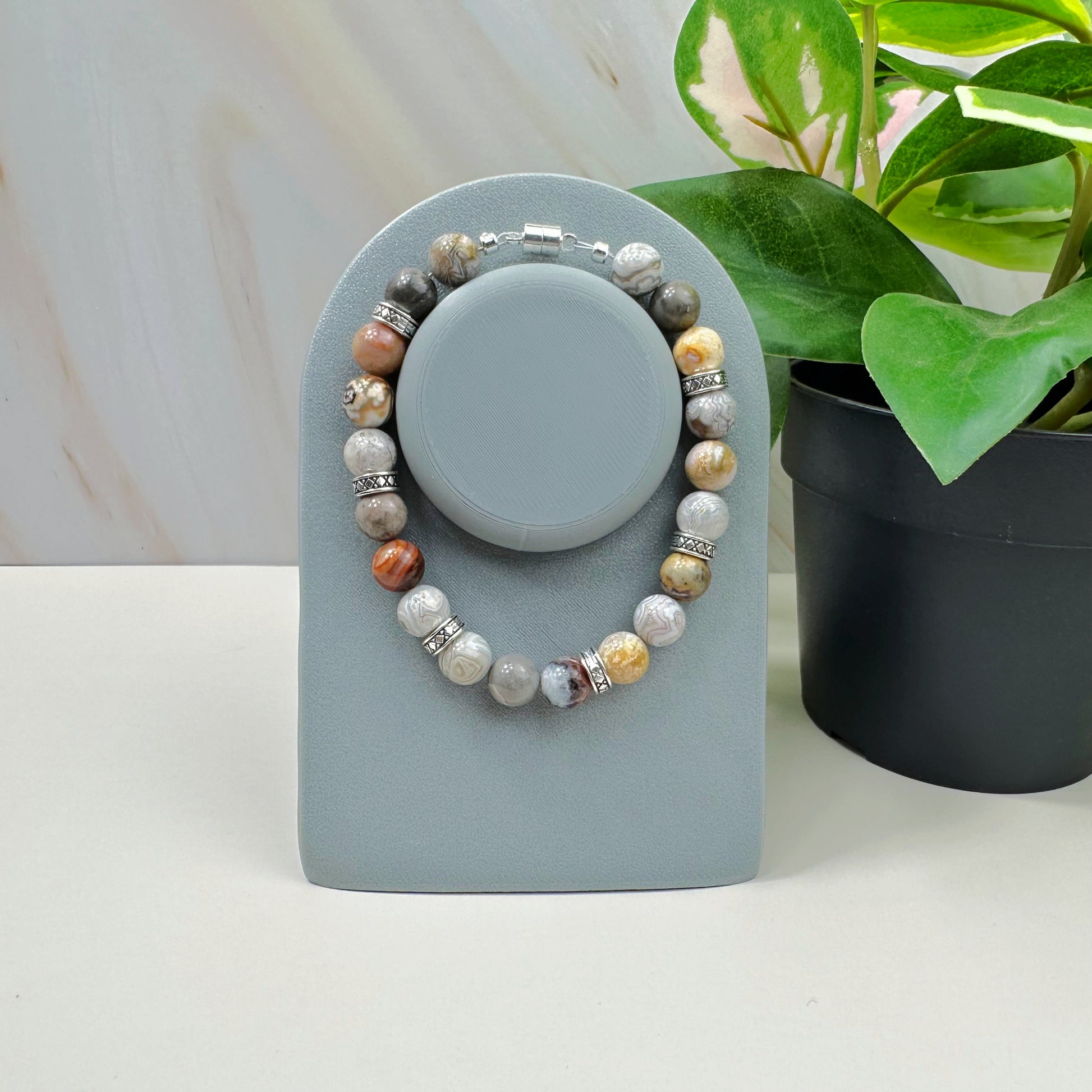 Set of beaded bracelets on a gray stand with a plant in the background