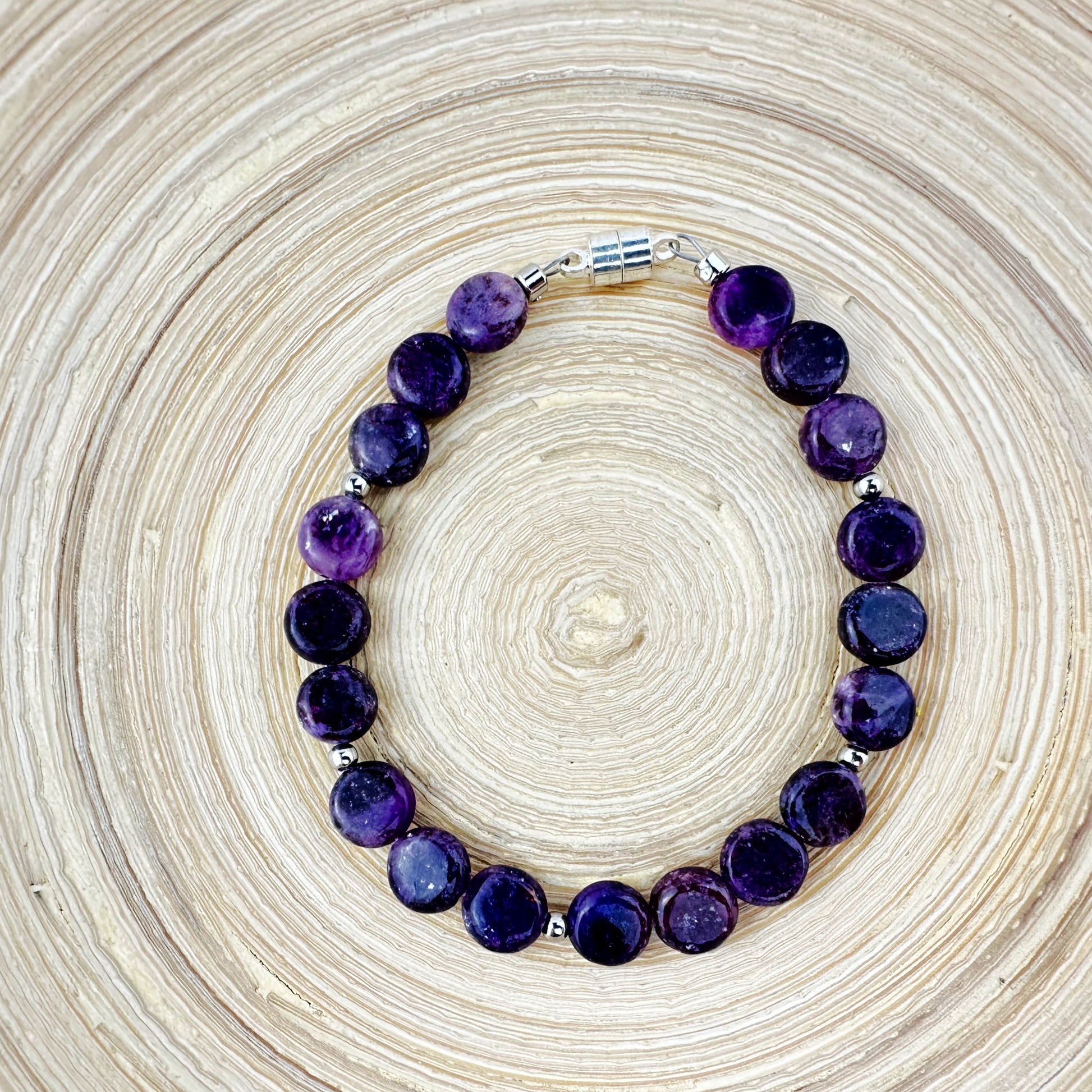 Purple beaded bracelet on a textured beige background