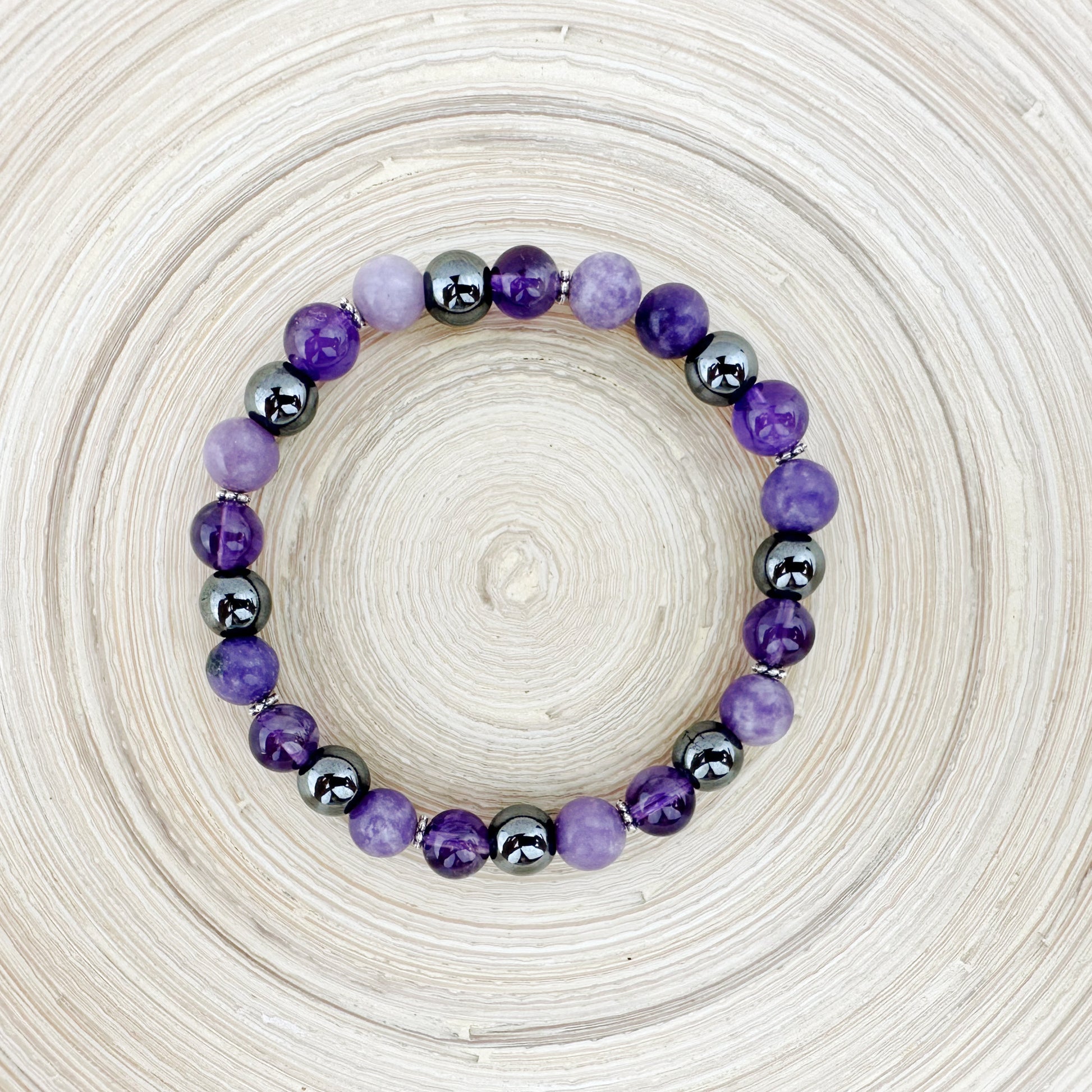 Beaded bracelet with purple and black beads on a textured beige background