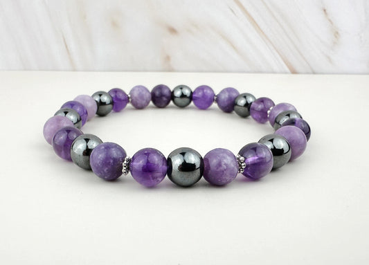 Purple and gray beaded bracelet on a white surface with a light wood background