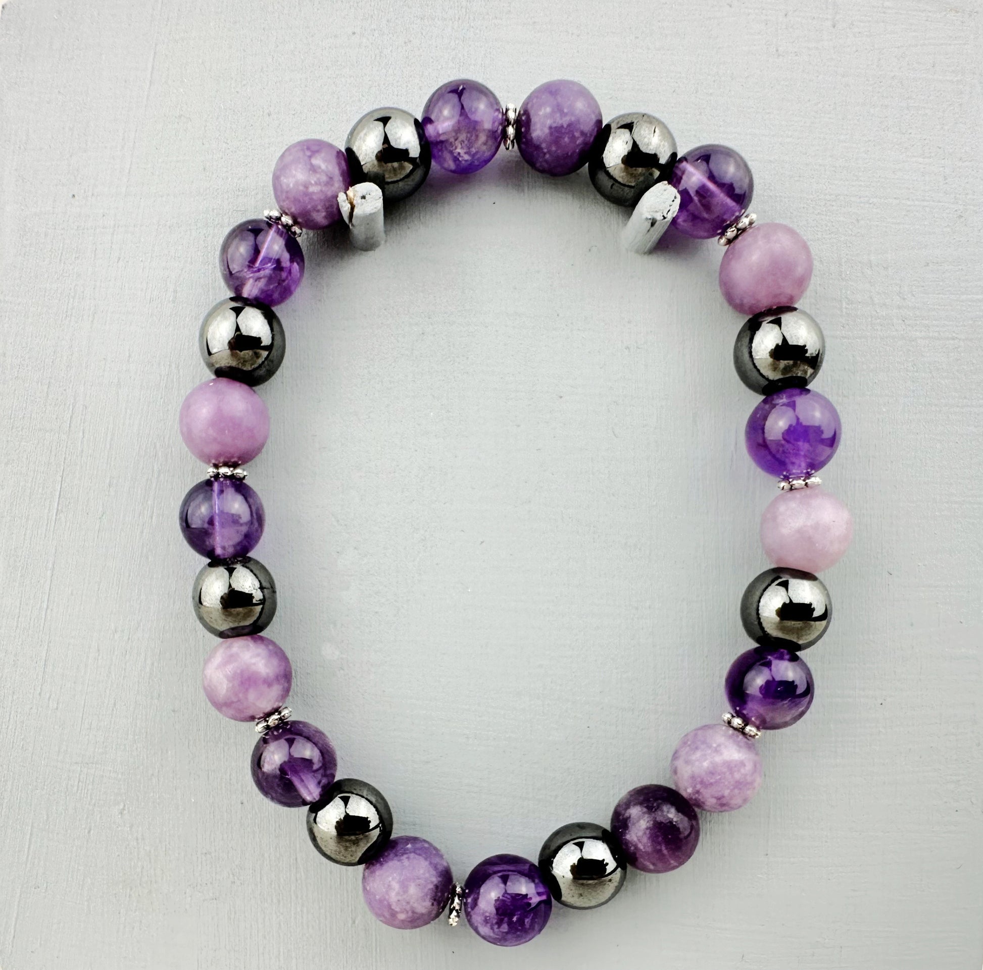 Beaded bracelet with purple, pink, and silver beads on a light gray background