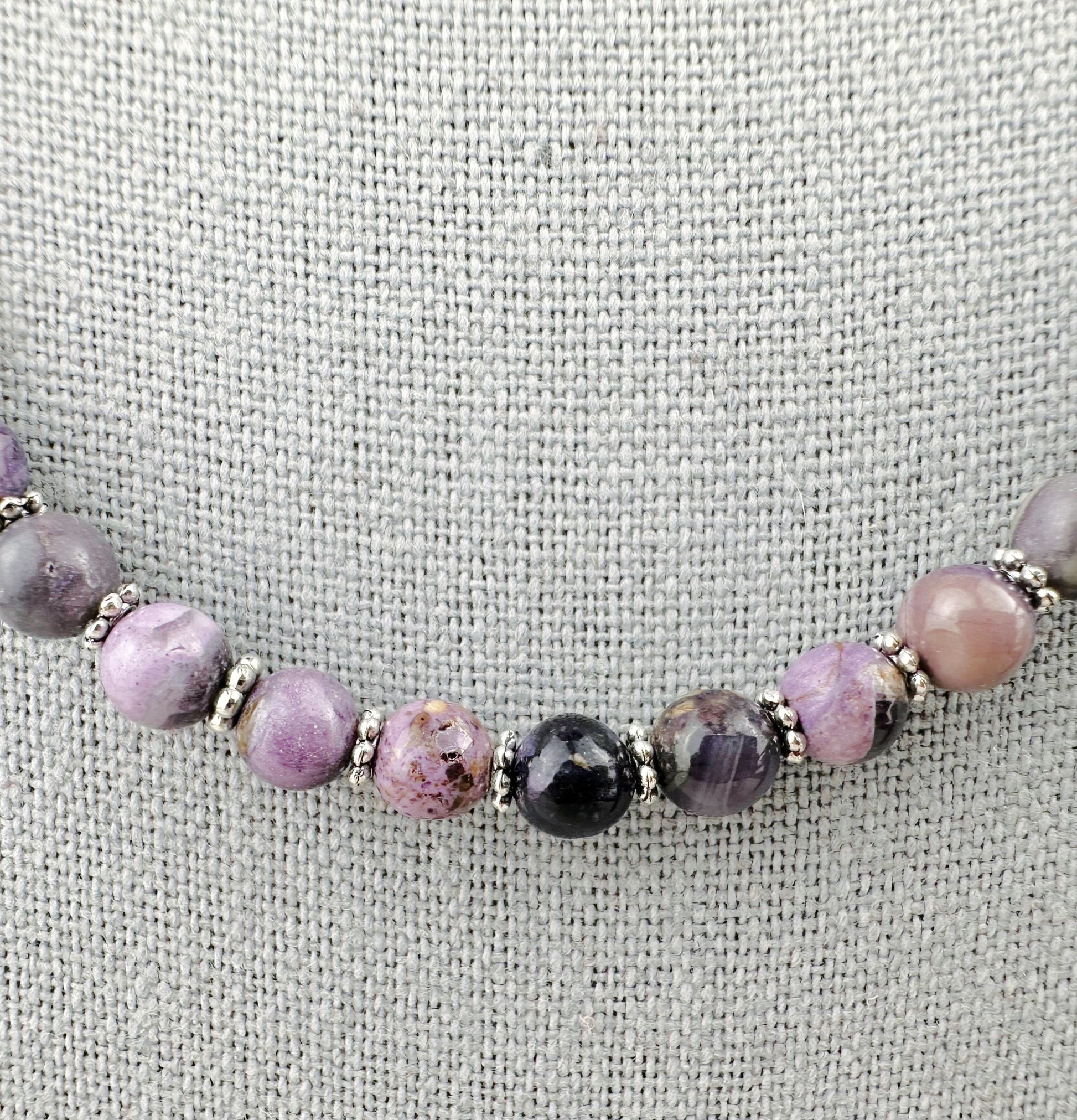 Beaded bracelet with purple and black beads on a textured fabric background