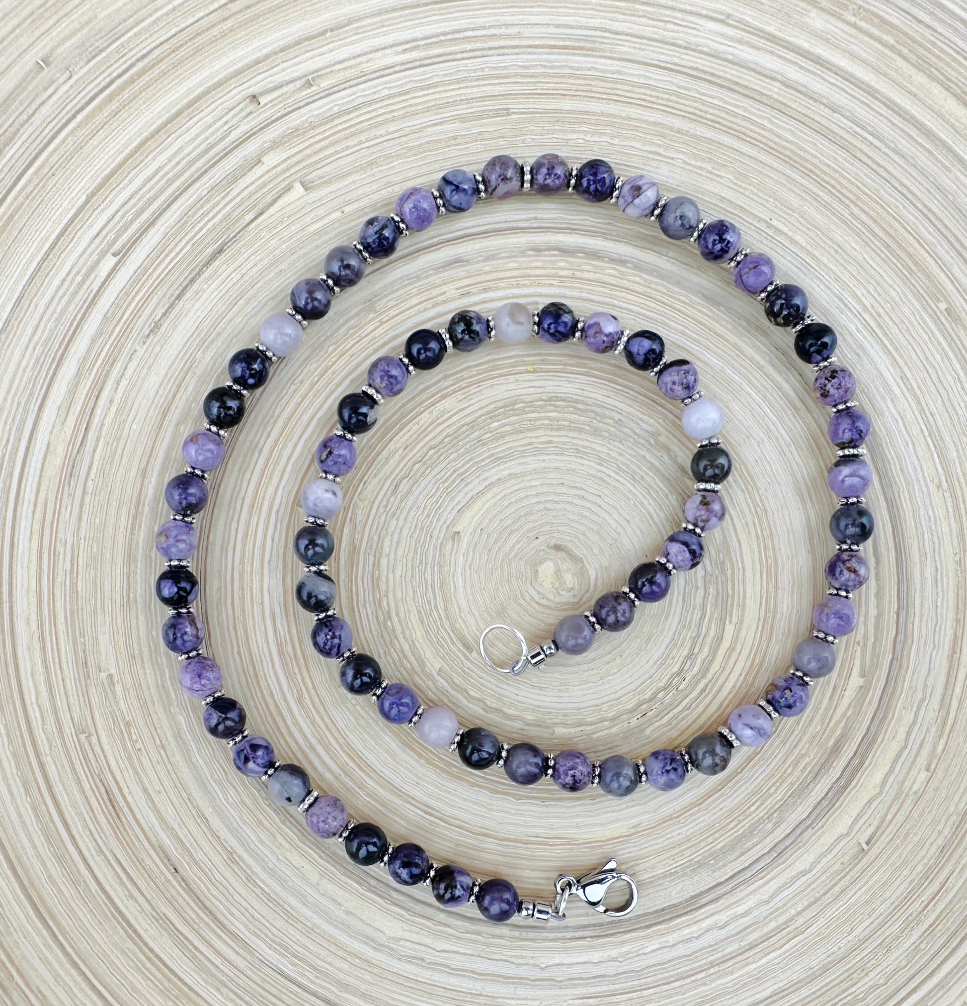 Necklace with purple and black beads on a textured beige background