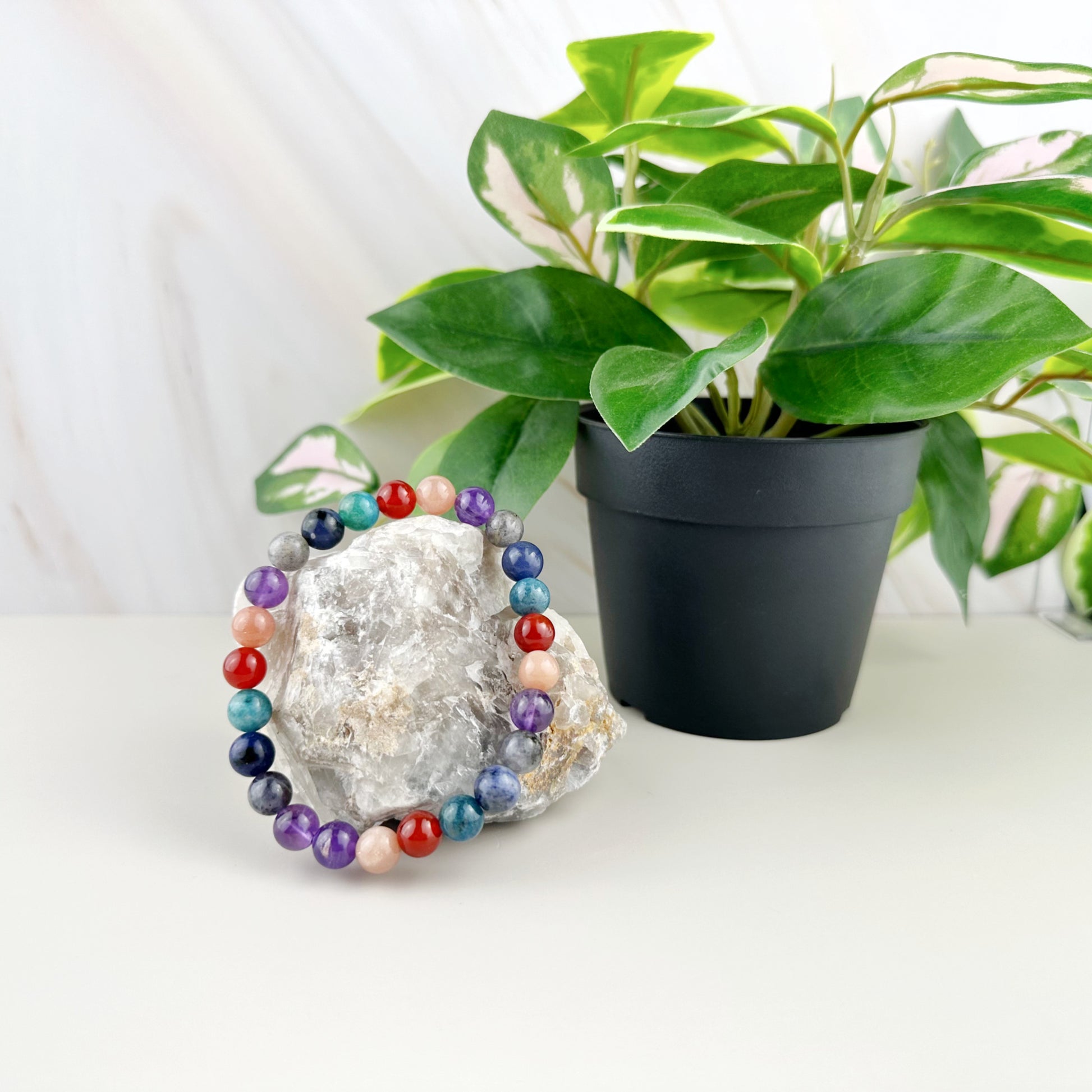 Colorful beaded bracelet on a crystal with a potted plant in the background