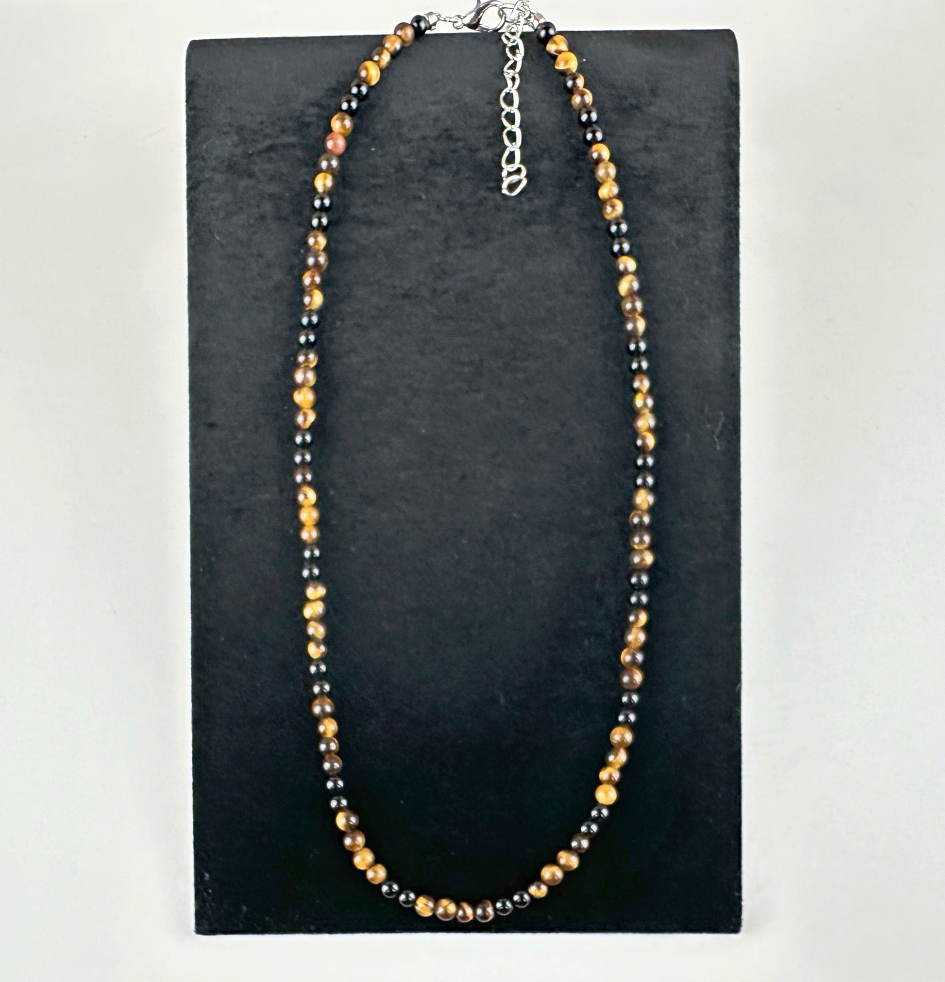Beaded necklace on a black stand with a white background