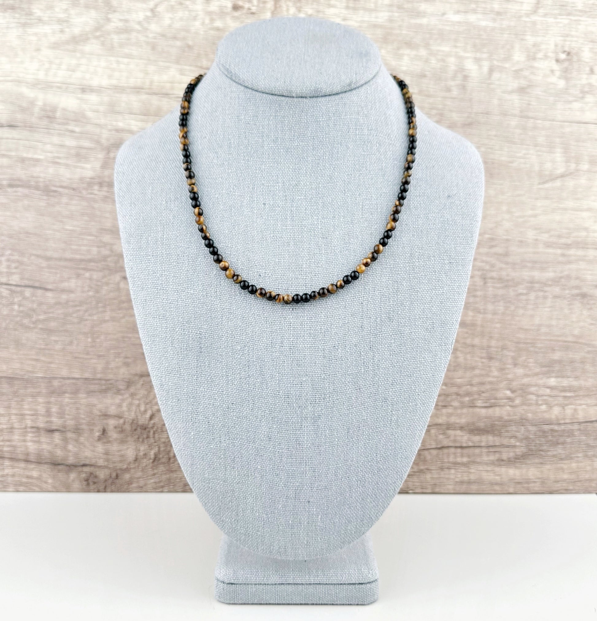Necklace on a gray bust against a wooden background